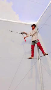 Worker Installing Shade Net On Structure
